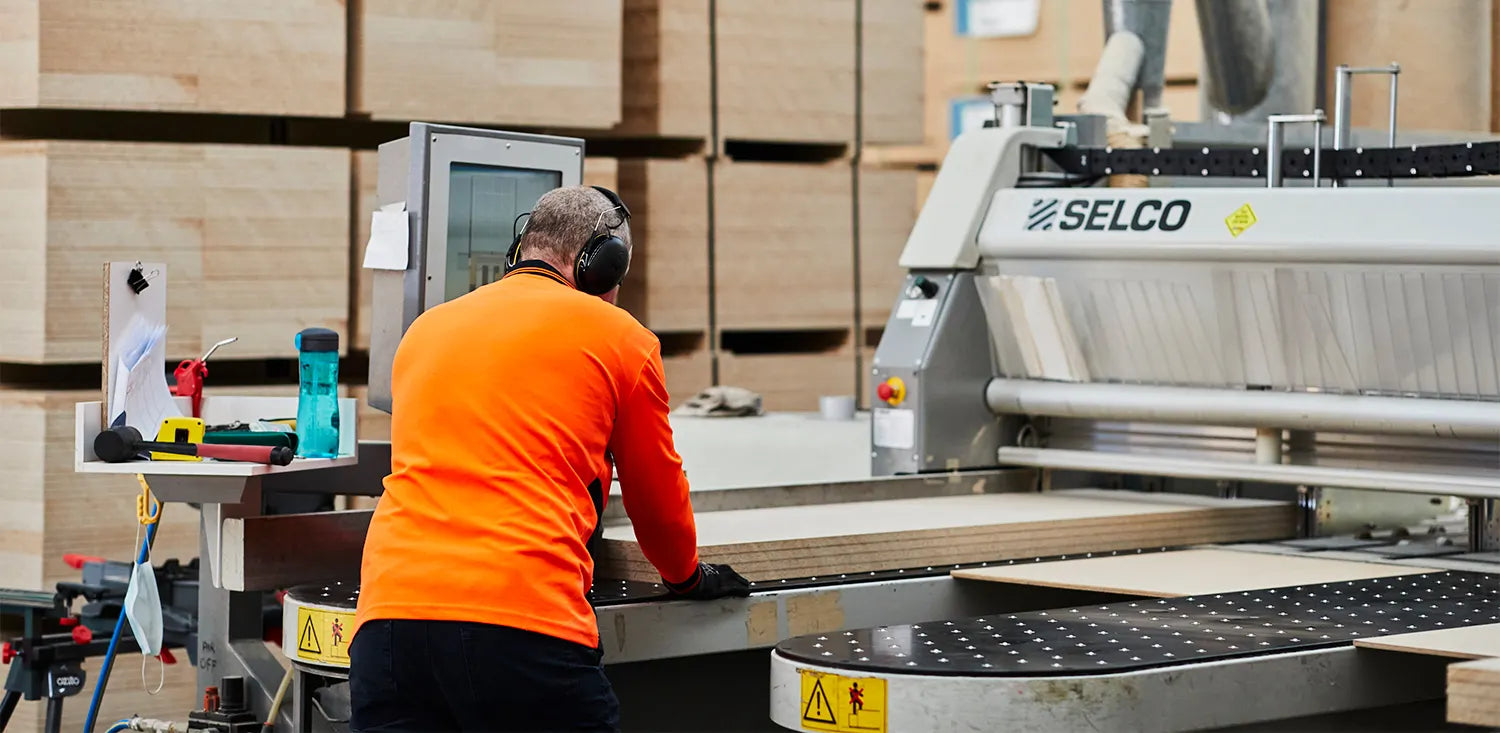 Interior image of Plyco's manufacturing warehouse with particleboard and MDF panels stacked behind the saw operator